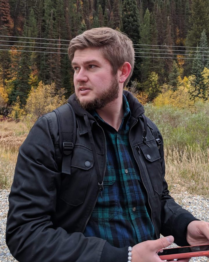 Blake Riding outdoors in front of an autumn forest